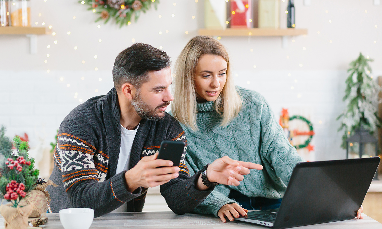 man and woman looking at laptop surrounded by Christmas decorations