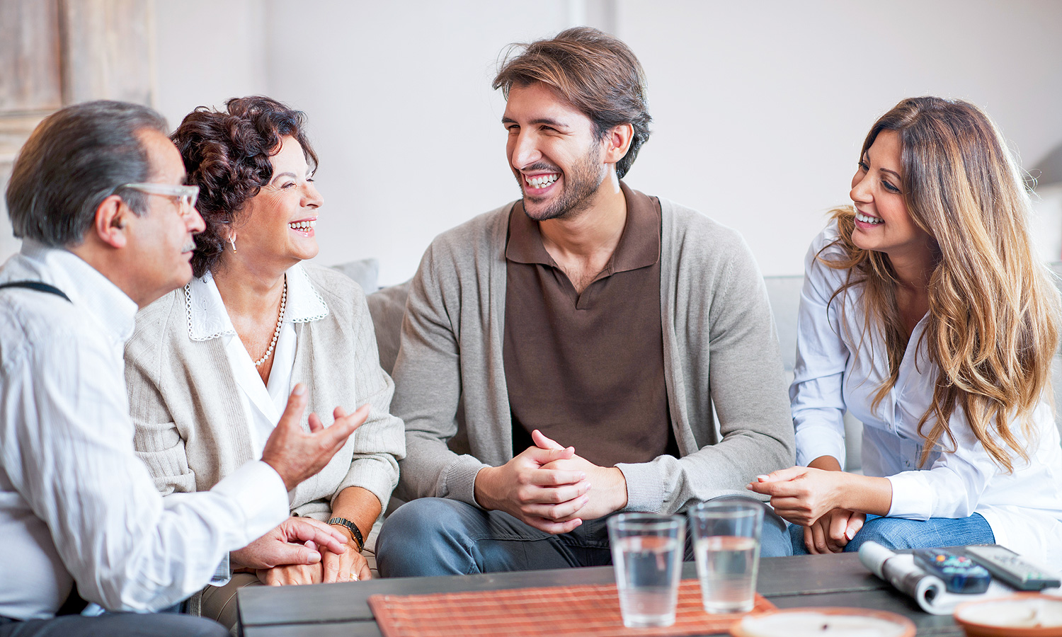 senior man and woman speaking to another man and woman while sitting at a table