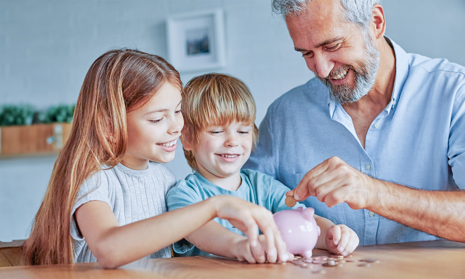 Dad helping his two children put money into a piggy bank