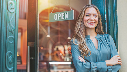 woman arms crossed standing in front of business door with an open sign